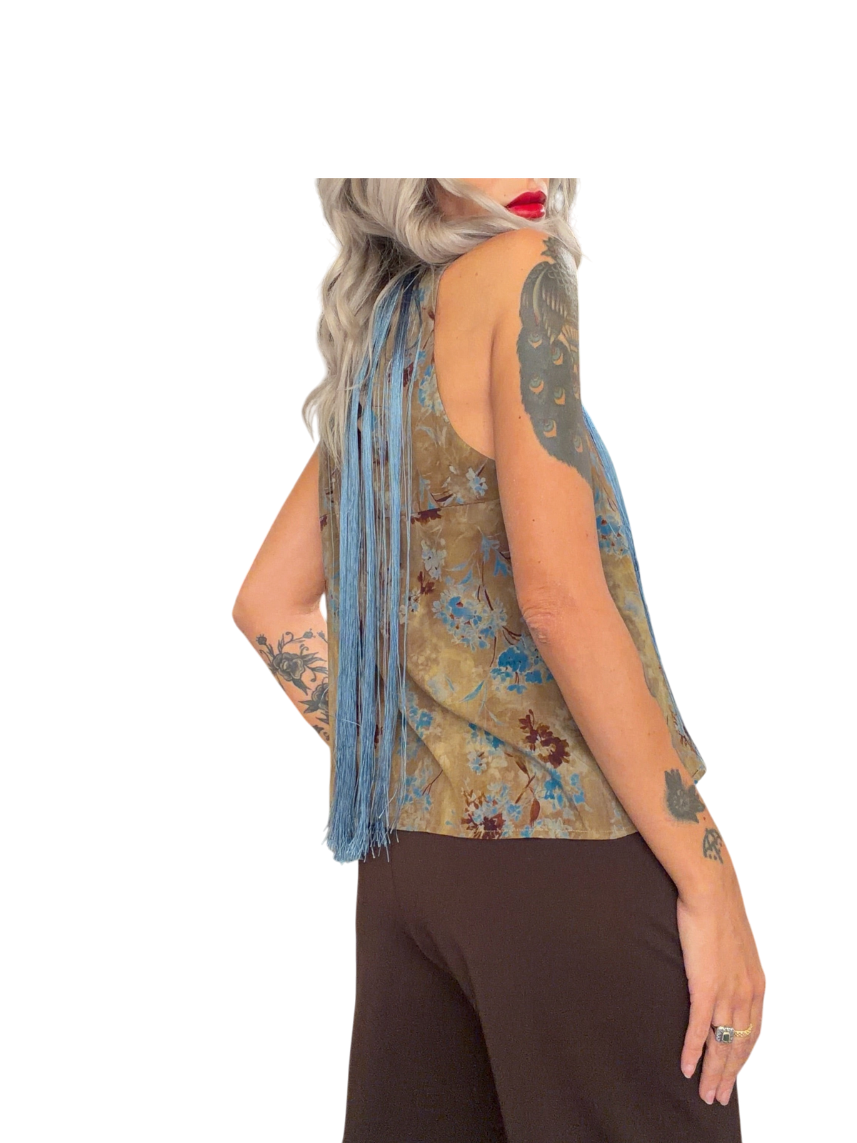 Modella indossa top smanicato Blaze Shop con stampa floreale beige e lunghe frange azzurre su sfondo bianco