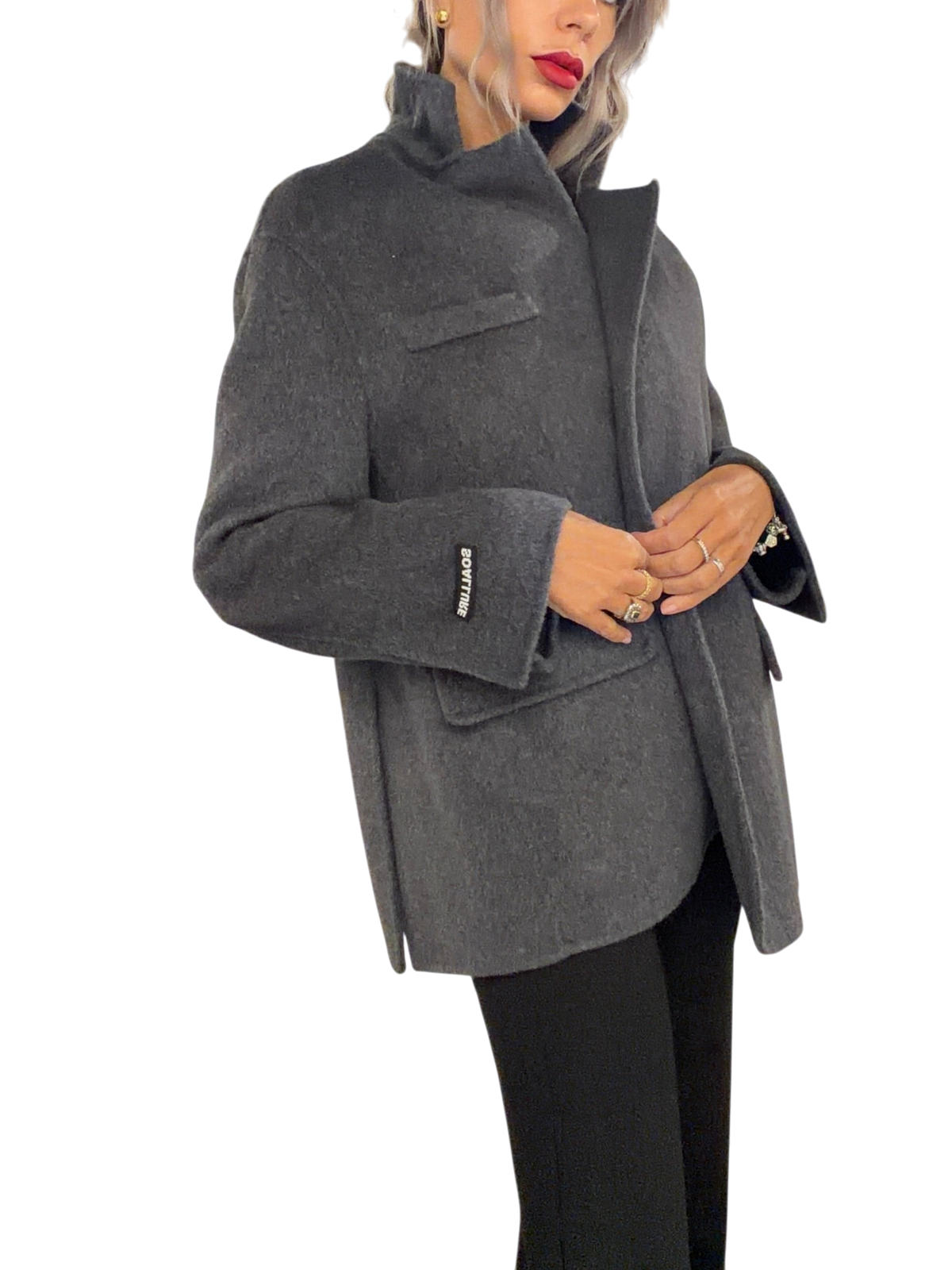 Modella indossa un cappotto corto Blaze Shop in lana grigio antracite con vestibilità oversize e logo sul polso