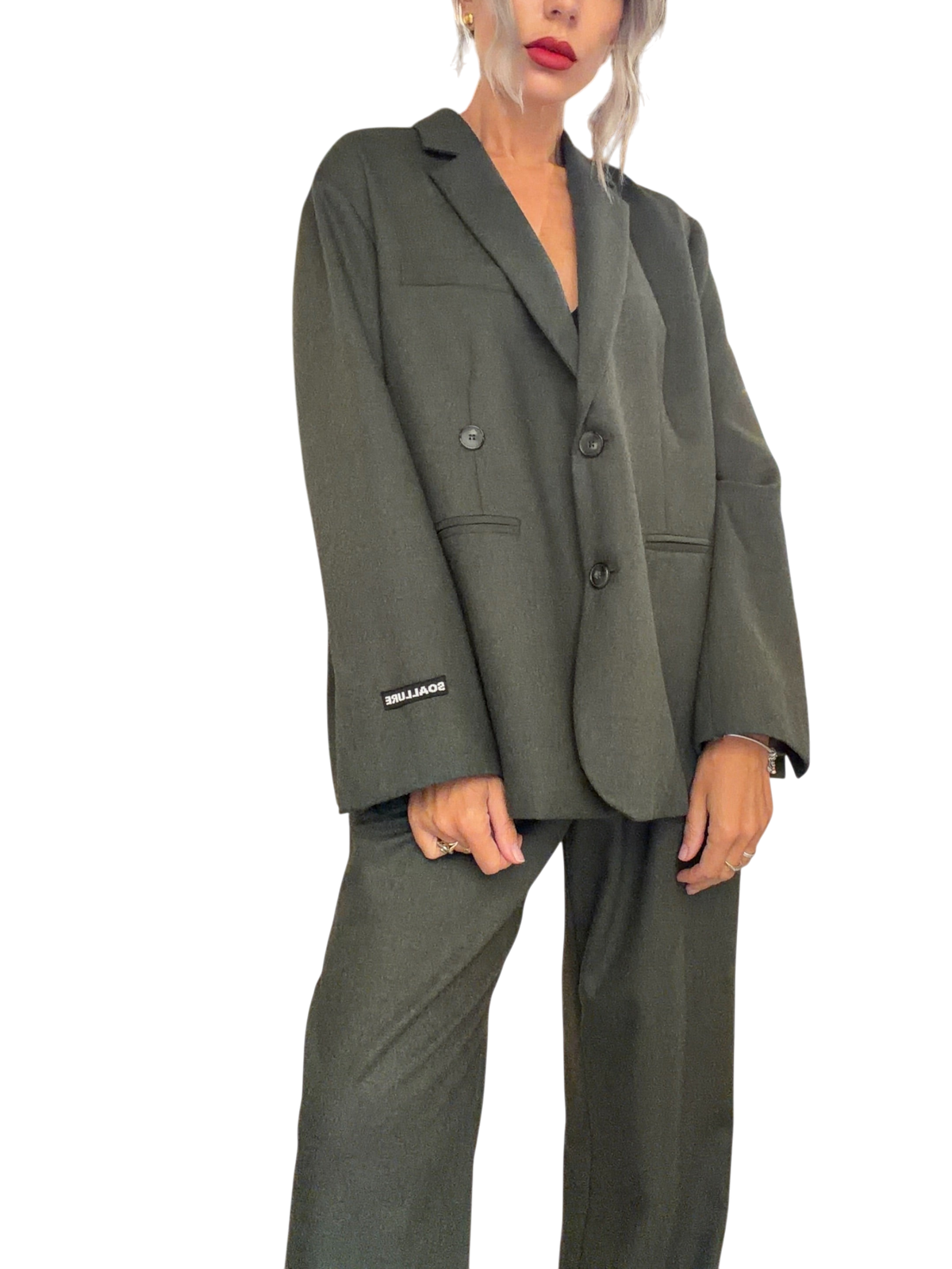 Modella indossa giacca doppiopetto oversize verde loden Blaze Shop con revers ampi e logo sul polso in negozio