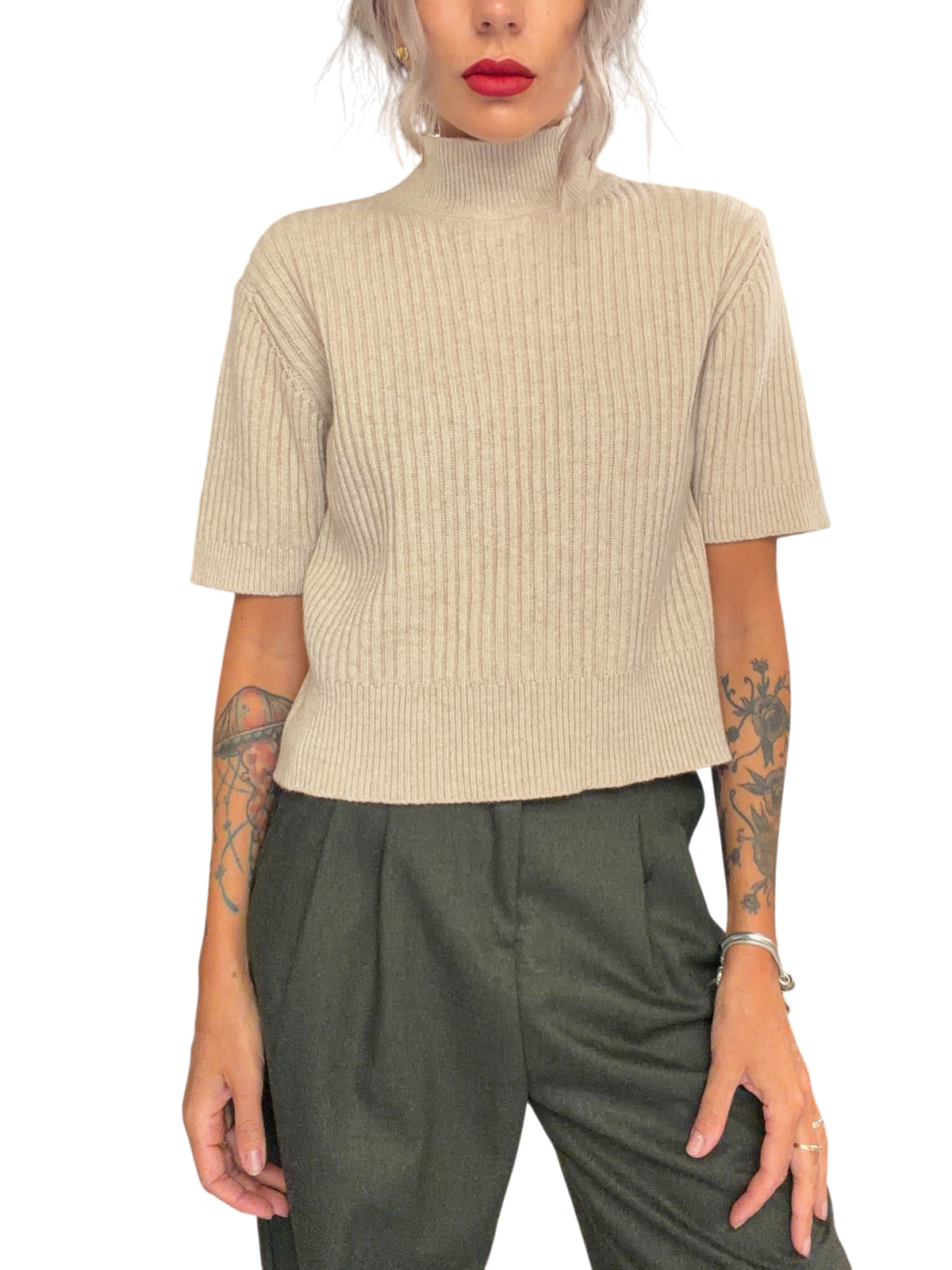 Modella indossa maglia Blaze Shop color avena a coste con collo alto e maniche corte in un negozio di abbigliamento